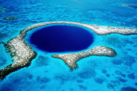 The Great Blue Hole is a giant submarine sinkhole off the coast of Belize. It lies near the center of Lighthouse Reef, a small atoll 70 km (43 mi) from the mainland and Belize City. The hole is circular in shape, over 300 m (984 ft) across and 108 m (354 ft) deep. It was formed during several episodes of quaternary glaciation when sea levels were much lower. Analysis of stalactites found in the Great Blue Hole shows that formation took place 153,000; 66,000; 60,000; and 15,000 years ago. As the ocean began to rise again, the cave was flooded. The Great Blue Hole is a part of the larger Belize Barrier Reef Reserve System, a World Heritage Site of the United Nations Educational, Scientific and Cultural Organization (UNESCO). What do you know about this sinkhole?